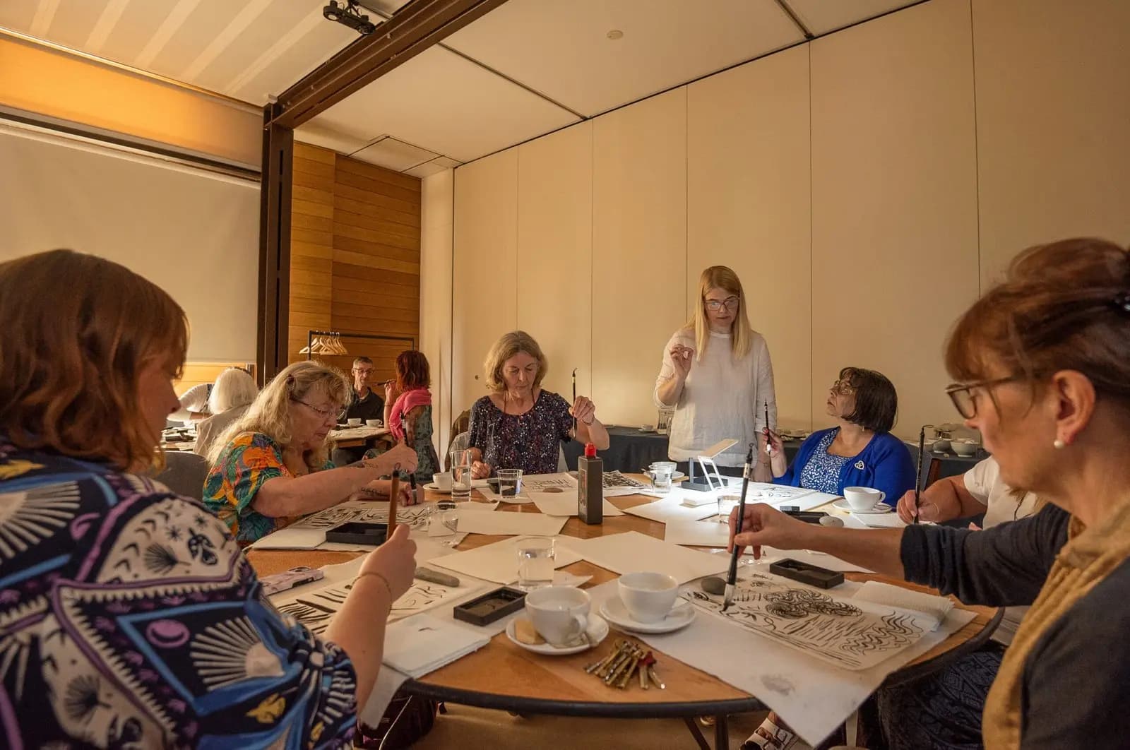 Jurga guiding a small Artivian painting group around a shared table