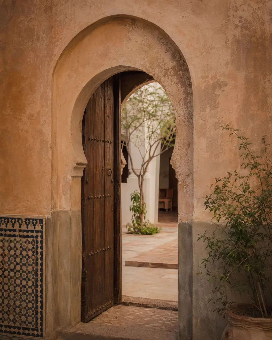An open arched doorway leading into a quiet Marrakech riad courtyard